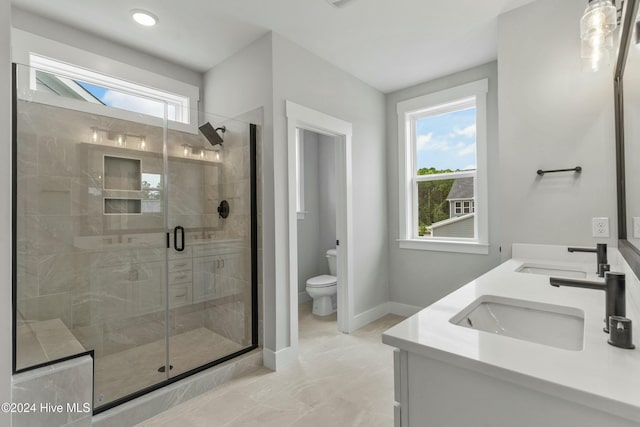 bathroom featuring plenty of natural light, toilet, a shower with door, and vanity