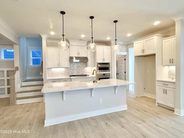 kitchen with under cabinet range hood, crown molding, gas cooktop, and a sink