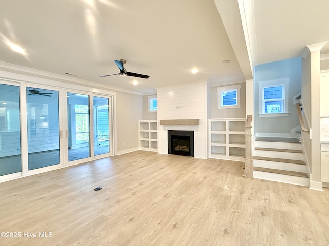 unfurnished living room featuring crown molding, a fireplace, baseboards, a ceiling fan, and light wood finished floors