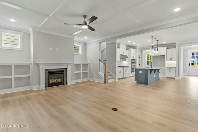 unfurnished living room featuring coffered ceiling, sink, ornamental molding, and light hardwood / wood-style floors