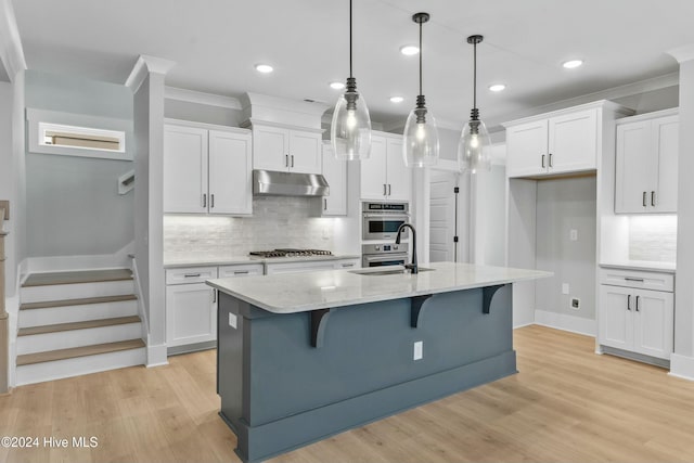 kitchen featuring sink, crown molding, a kitchen island with sink, white cabinetry, and decorative light fixtures