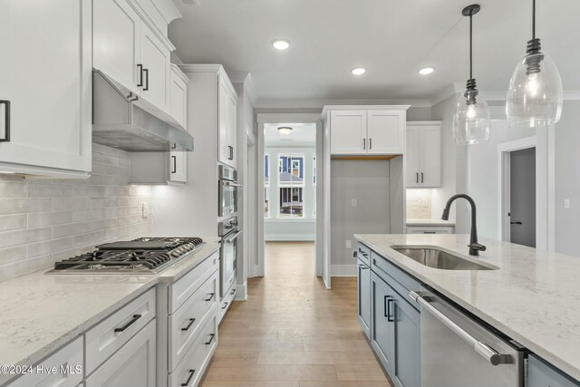 kitchen featuring white cabinetry, hanging light fixtures, a kitchen island with sink, double oven, and light stone countertops