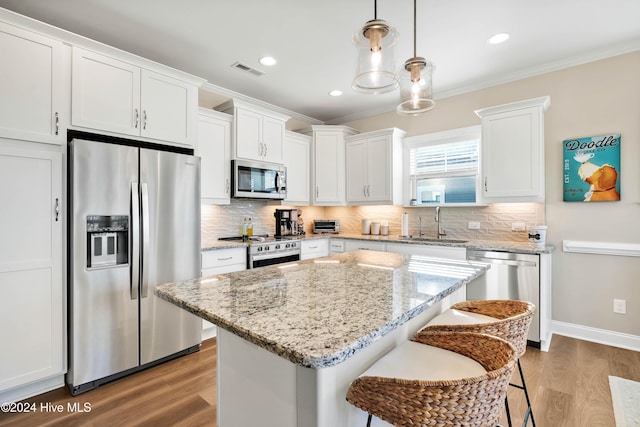 kitchen with white cabinetry, a kitchen island, stainless steel appliances, and decorative light fixtures