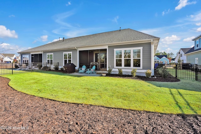 rear view of house with a sunroom, a patio area, and a yard