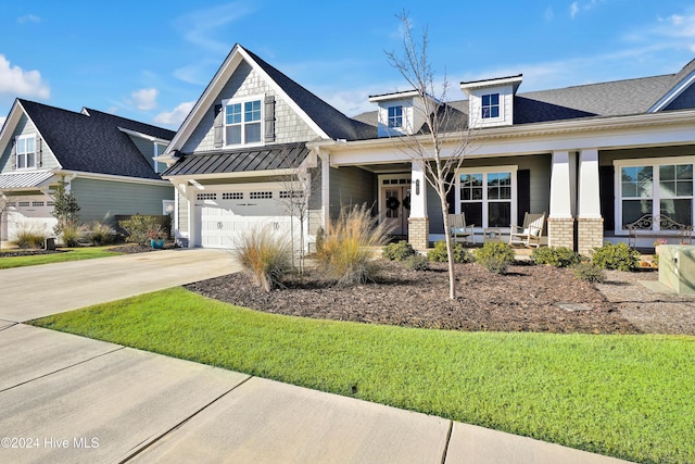 view of front of house featuring covered porch, a garage, and a front yard