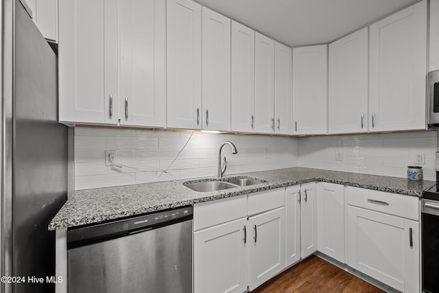 kitchen with appliances with stainless steel finishes, light stone counters, sink, dark hardwood / wood-style floors, and white cabinetry