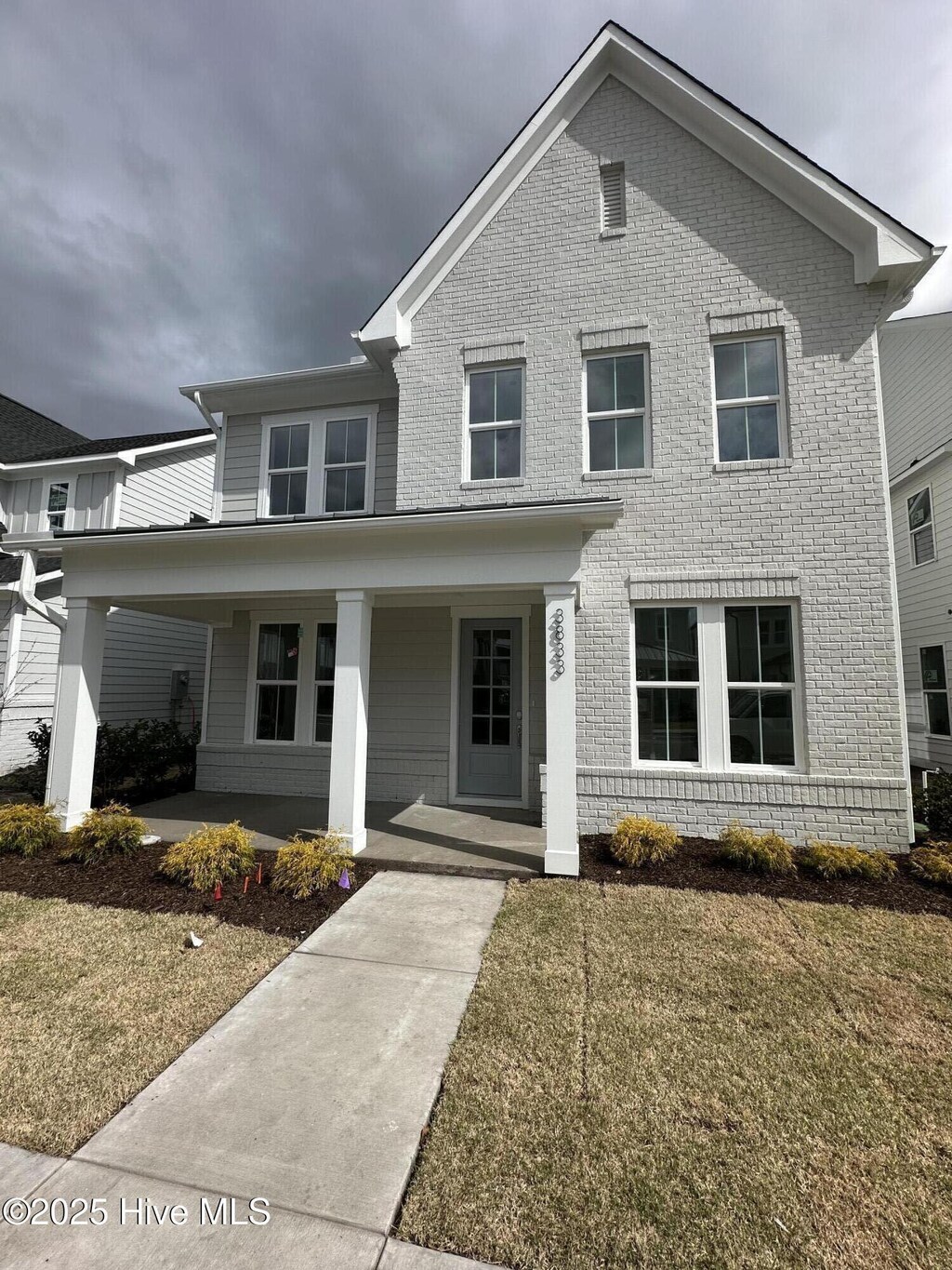 view of front facade featuring a standing seam roof, roof with shingles, a porch, and brick siding