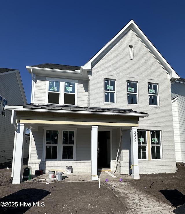 view of front facade featuring metal roof, a porch, a standing seam roof, and brick siding