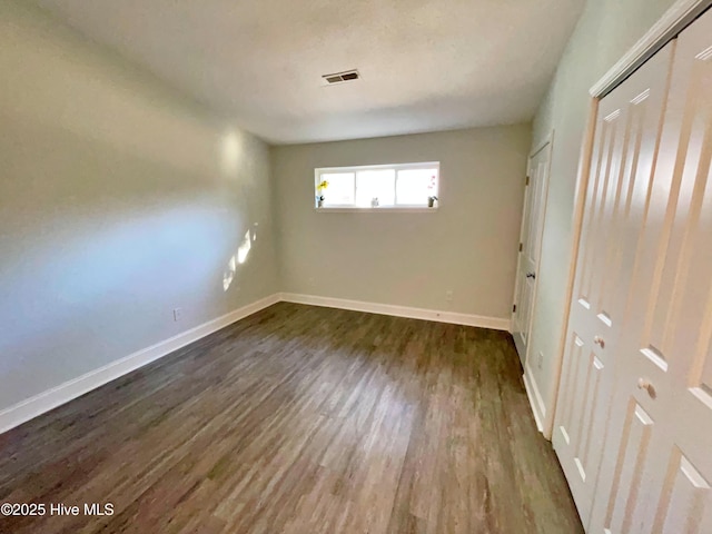 unfurnished bedroom with dark wood-type flooring and a closet