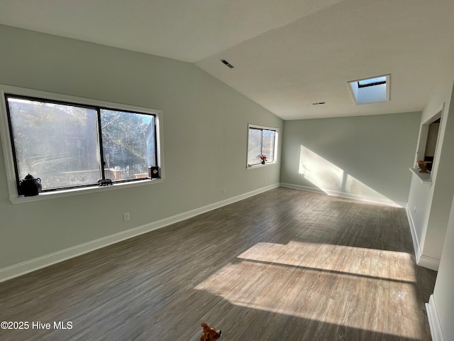 spare room with dark hardwood / wood-style flooring and vaulted ceiling with skylight