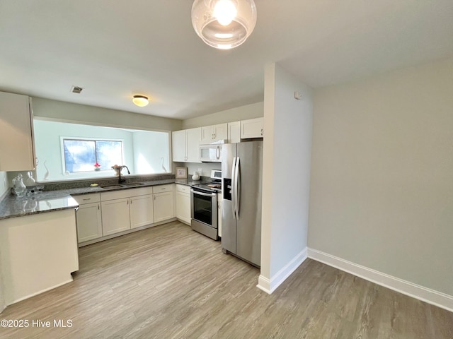 kitchen with stainless steel appliances, sink, white cabinets, and light hardwood / wood-style floors