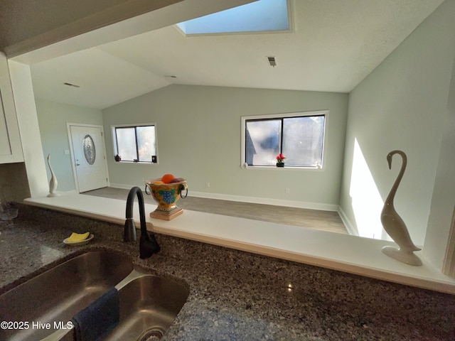 details with white cabinetry, stone countertops, a skylight, and sink