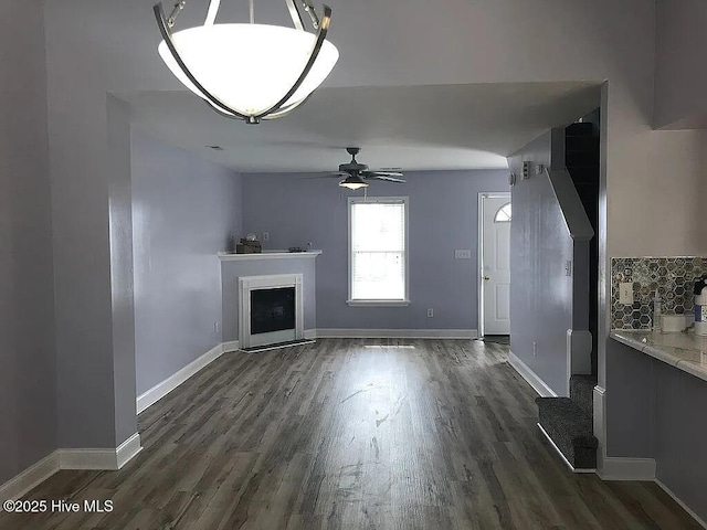 unfurnished living room with ceiling fan and dark wood-type flooring