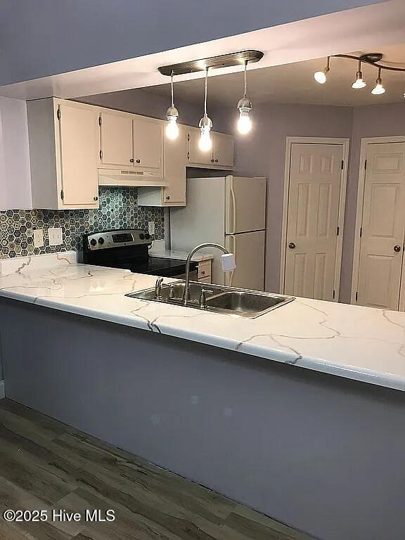 kitchen with sink, white refrigerator, white cabinetry, hanging light fixtures, and stainless steel range with electric cooktop