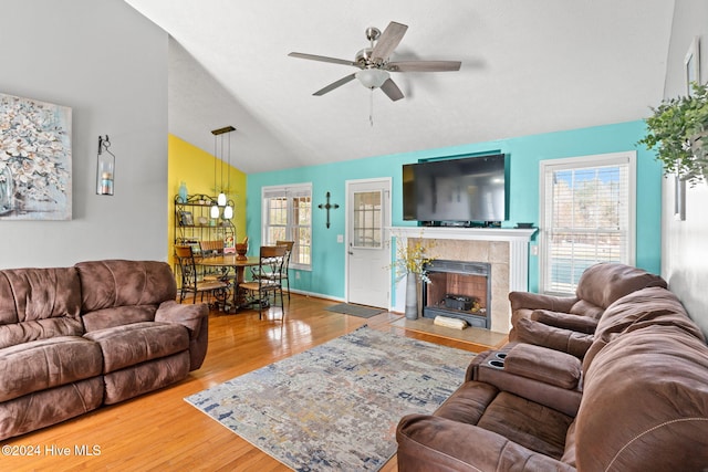 living room featuring a tile fireplace, wood-type flooring, high vaulted ceiling, and ceiling fan