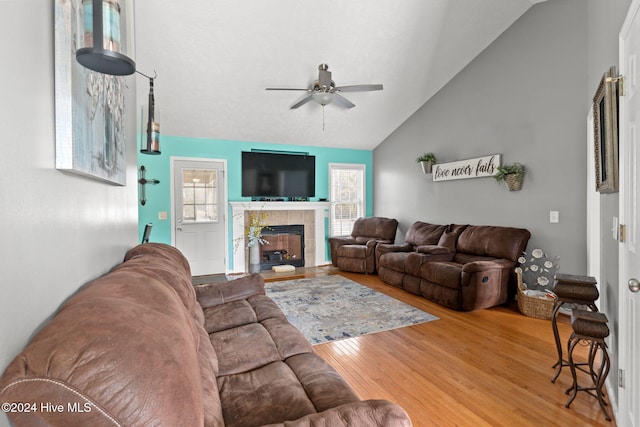 living room featuring a tile fireplace, hardwood / wood-style floors, vaulted ceiling, and ceiling fan