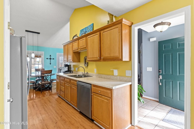 kitchen featuring sink, decorative light fixtures, lofted ceiling, appliances with stainless steel finishes, and light wood-type flooring