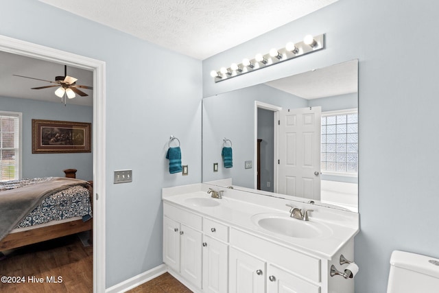 bathroom with ceiling fan, a textured ceiling, toilet, vanity, and hardwood / wood-style flooring