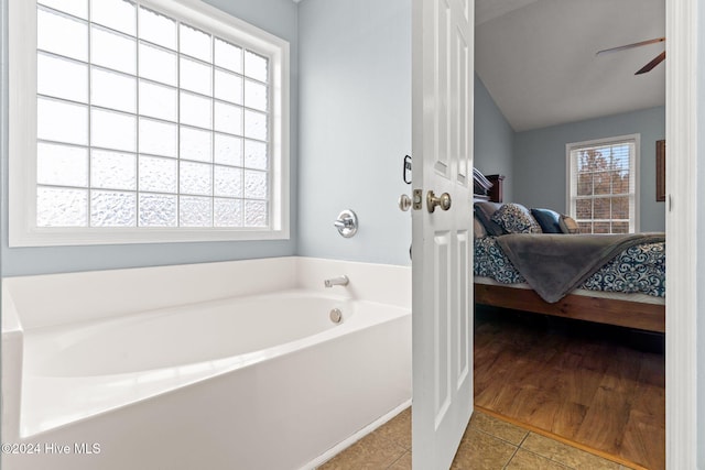 bathroom featuring hardwood / wood-style floors, ceiling fan, and a tub to relax in