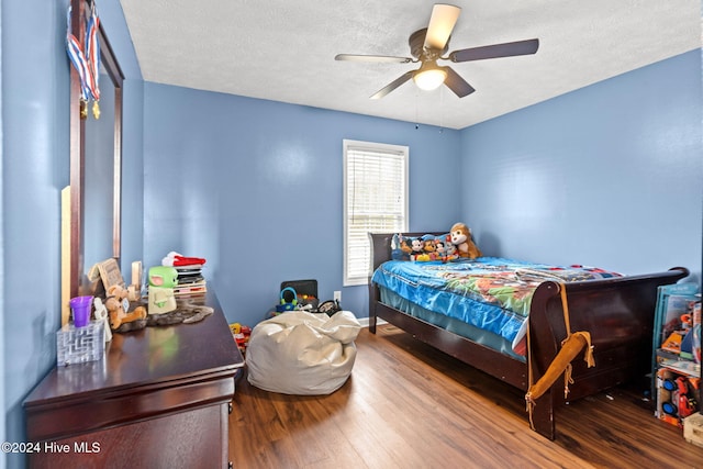 bedroom with hardwood / wood-style floors, ceiling fan, and a textured ceiling