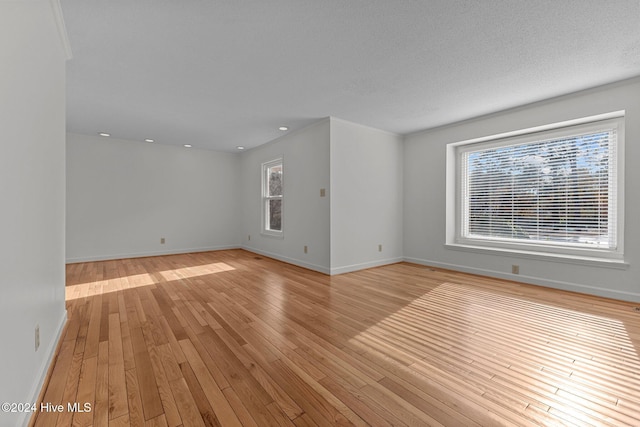 empty room with a textured ceiling and light hardwood / wood-style floors