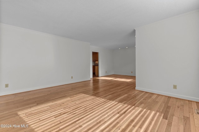 spare room with ornamental molding, a textured ceiling, and light hardwood / wood-style flooring