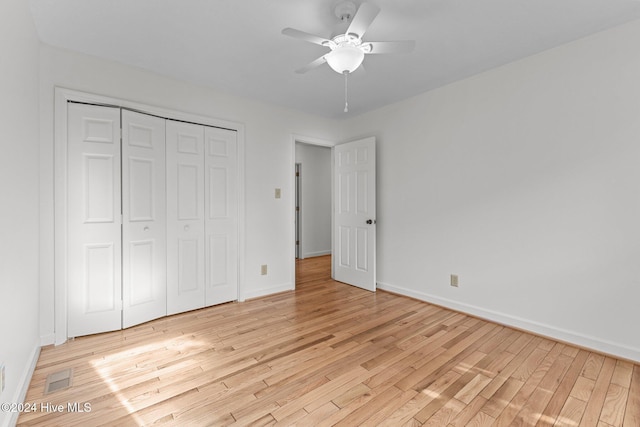 unfurnished bedroom featuring ceiling fan, light wood-type flooring, and a closet