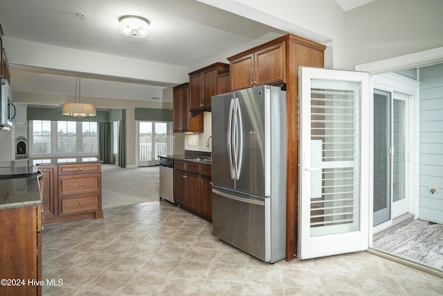 kitchen with sink, stainless steel appliances, dark stone countertops, decorative light fixtures, and light tile patterned flooring