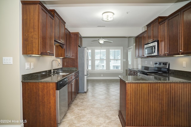 kitchen with kitchen peninsula, sink, dark stone counters, and appliances with stainless steel finishes