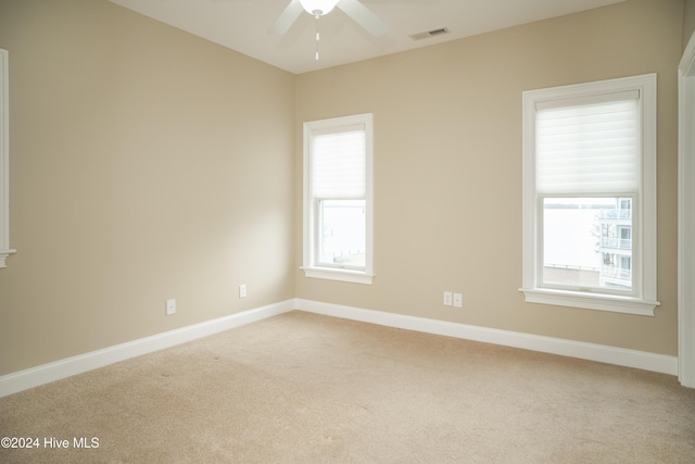 empty room with light carpet, ceiling fan, and a healthy amount of sunlight