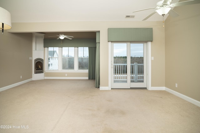 unfurnished living room featuring ceiling fan and light carpet