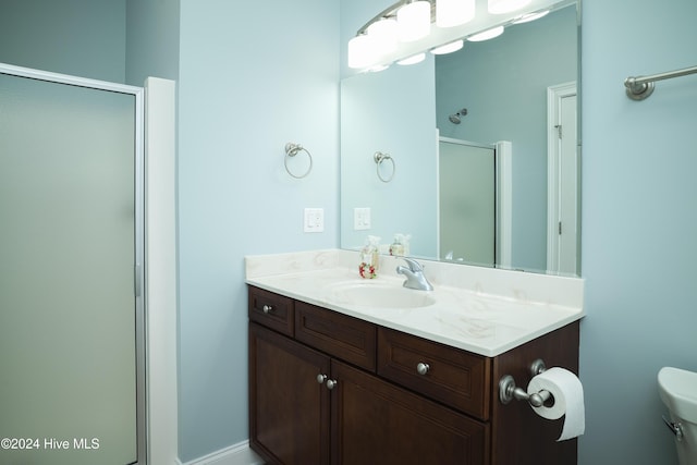 bathroom featuring vanity, toilet, and a shower with door