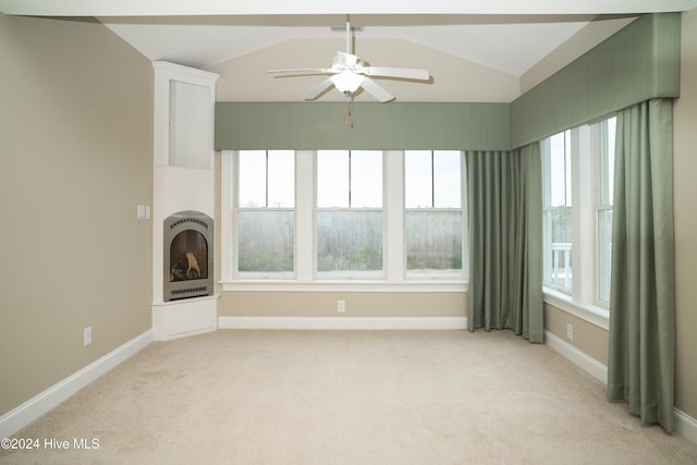 unfurnished living room with ceiling fan, light colored carpet, a wealth of natural light, and vaulted ceiling