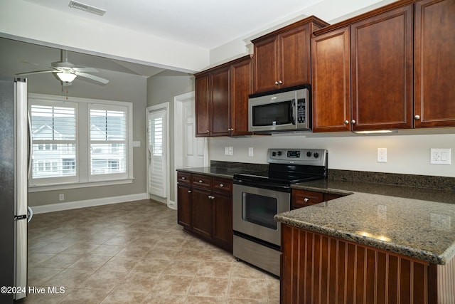 kitchen with ceiling fan, dark stone countertops, light tile patterned floors, and stainless steel appliances