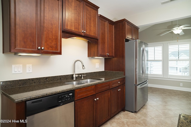 kitchen with appliances with stainless steel finishes, ceiling fan, dark stone countertops, and sink