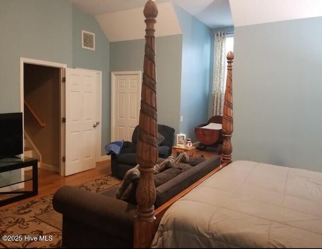 bedroom featuring visible vents, lofted ceiling, and light wood-type flooring