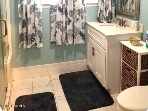 bathroom featuring tile patterned floors, vanity, toilet, and a stall shower