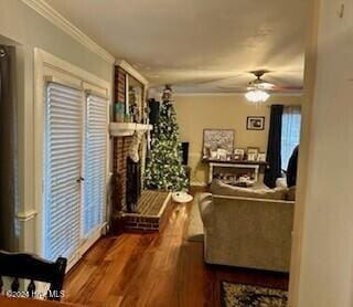 living room featuring dark hardwood / wood-style flooring, ceiling fan, a fireplace, and crown molding