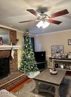 living room featuring crown molding, a fireplace, ceiling fan, and hardwood / wood-style flooring