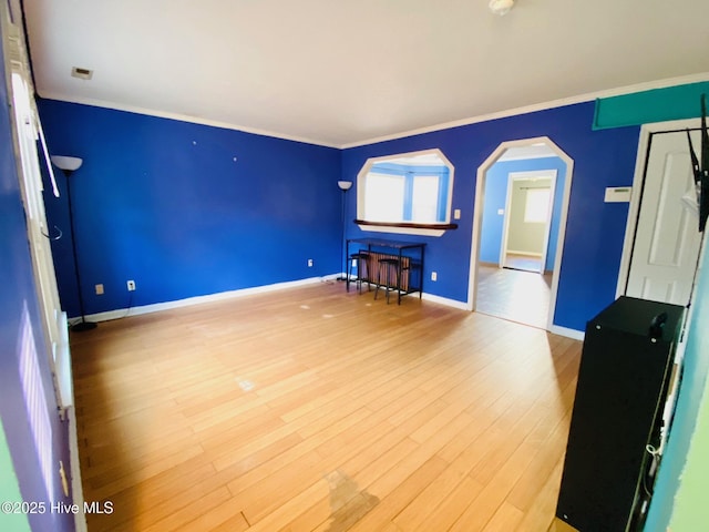 unfurnished living room featuring crown molding and hardwood / wood-style floors