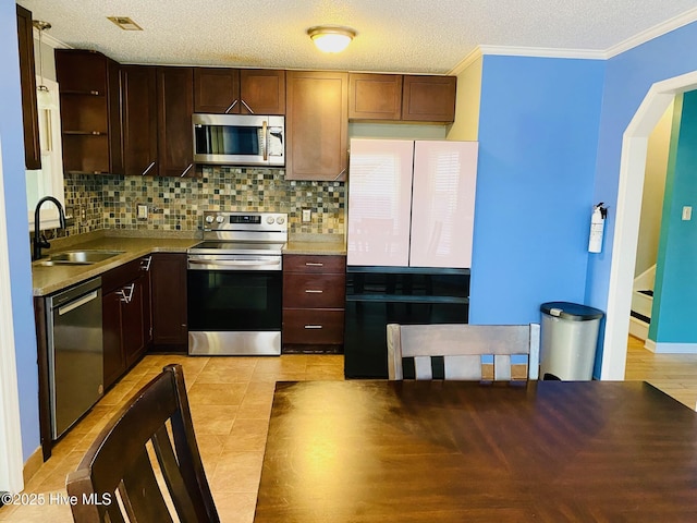 kitchen featuring a textured ceiling, appliances with stainless steel finishes, decorative backsplash, sink, and crown molding