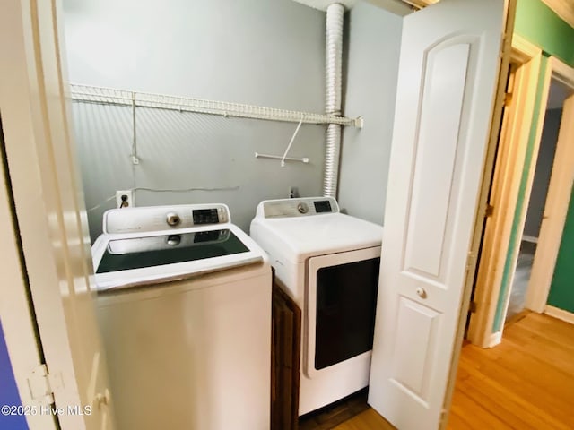 clothes washing area featuring washer and dryer and hardwood / wood-style flooring