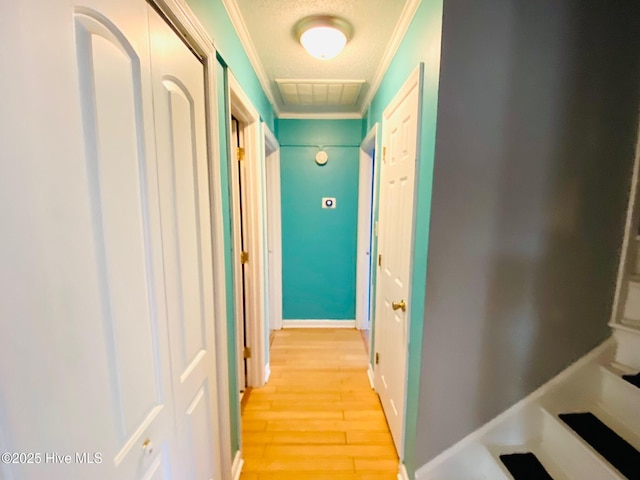 hallway with a textured ceiling, ornamental molding, and light hardwood / wood-style flooring