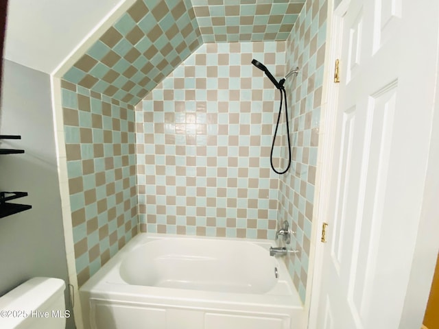 bathroom featuring tiled shower / bath combo and toilet