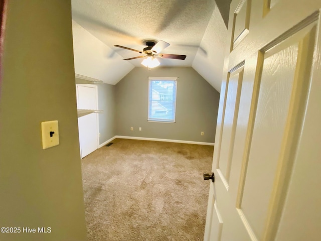 additional living space with ceiling fan, light carpet, a textured ceiling, and lofted ceiling