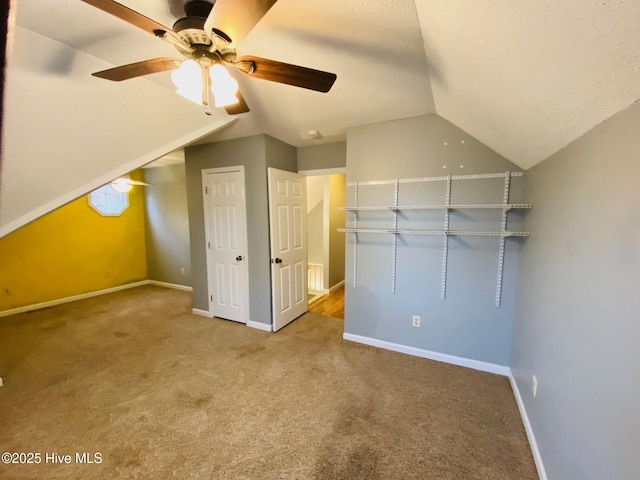 additional living space with vaulted ceiling, ceiling fan, carpet, and a textured ceiling