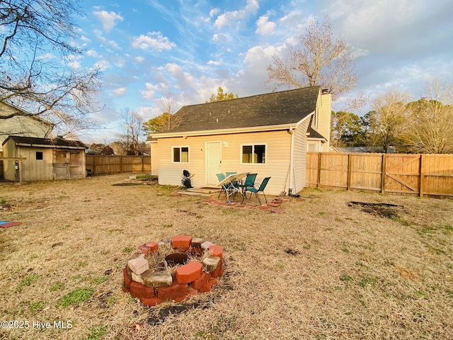 back of property featuring an outdoor fire pit, a yard, and an outdoor structure