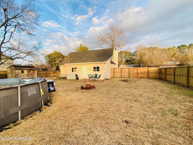 back of property featuring an outdoor fire pit and a lawn