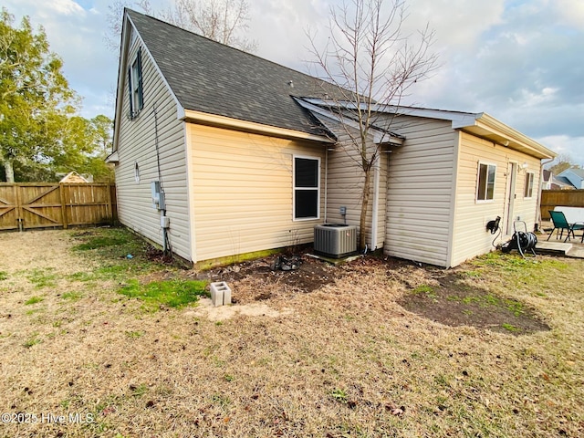 rear view of house featuring central AC and a lawn