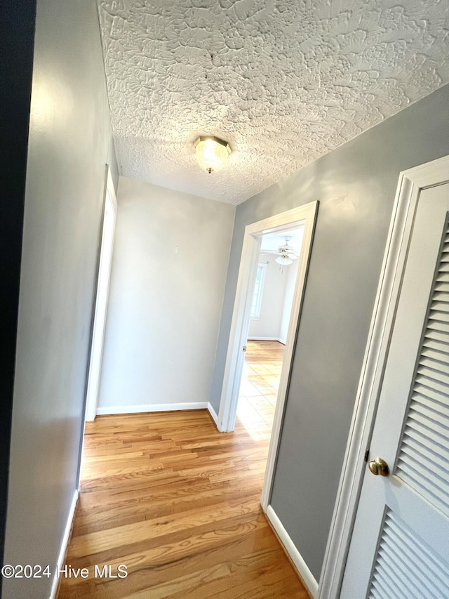 hall featuring a textured ceiling and light hardwood / wood-style floors